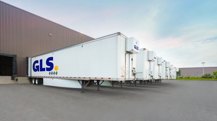 White GLS trailers docked at a warehouse.