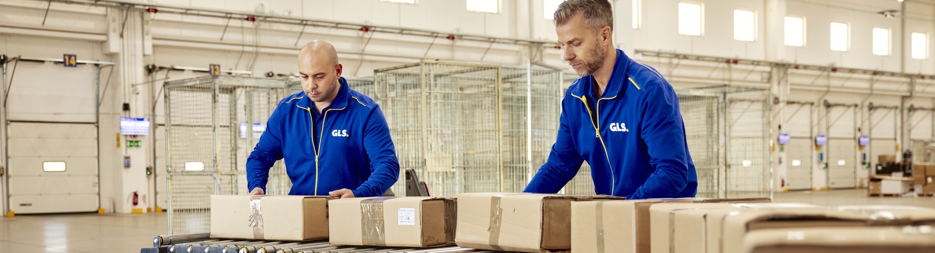 Two employees sorting packages on a conveyor