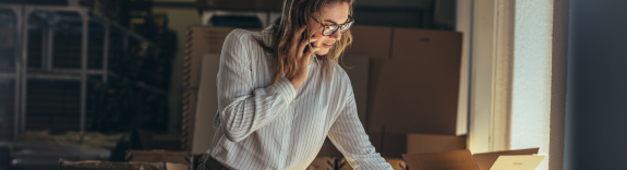A woman talking on the phone looking down at an open box